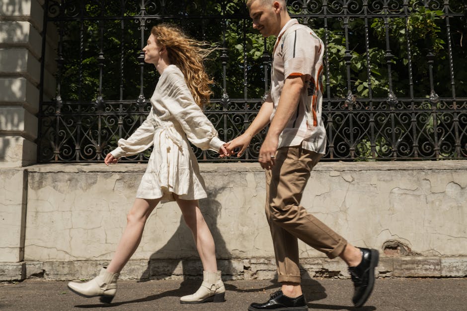 Young couple holding hands while walking on a sunny day, capturing a moment of togetherness.