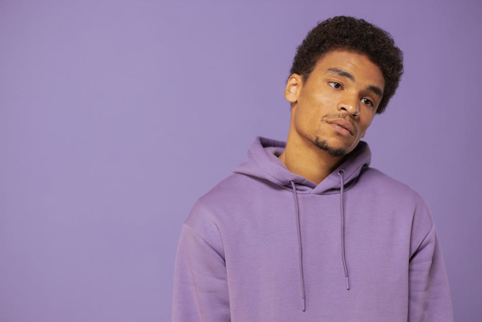 Portrait of an adult black man wearing a purple hoodie against a matching purple background.