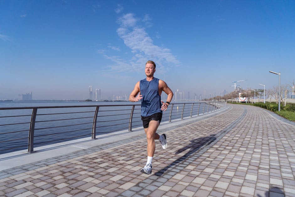 A man jogging along the scenic waterfront promenade in Dubai, UAE, on a sunny day.