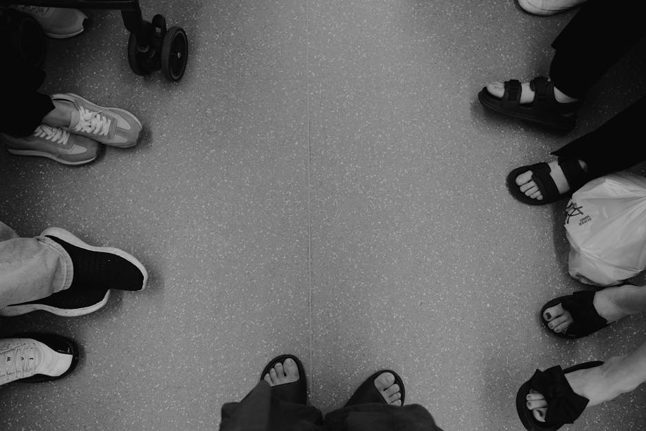 Black and white photo showcasing diverse footwear on a public transit floor.