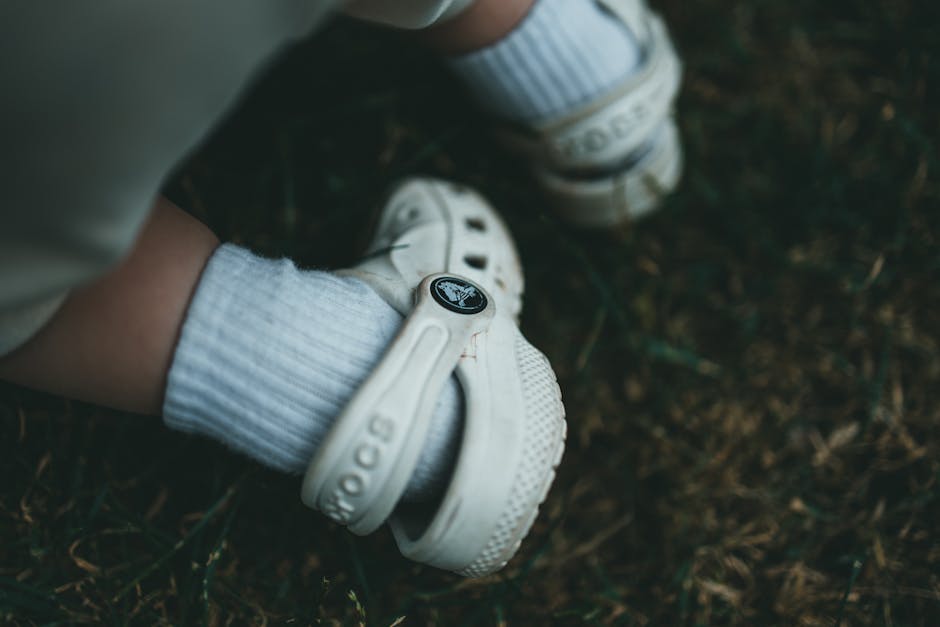 Close-up of a child's foot wearing a white sandal on grass outside. Perfect for lifestyle and fashion themes.