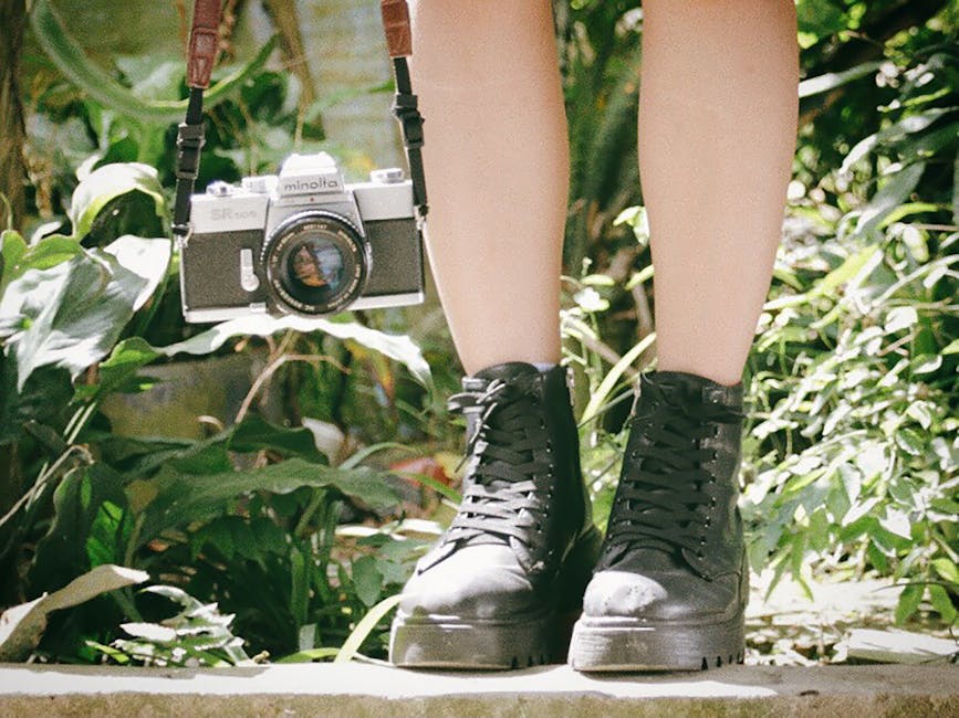 Legs with black boots and vintage camera in a lush garden setting.