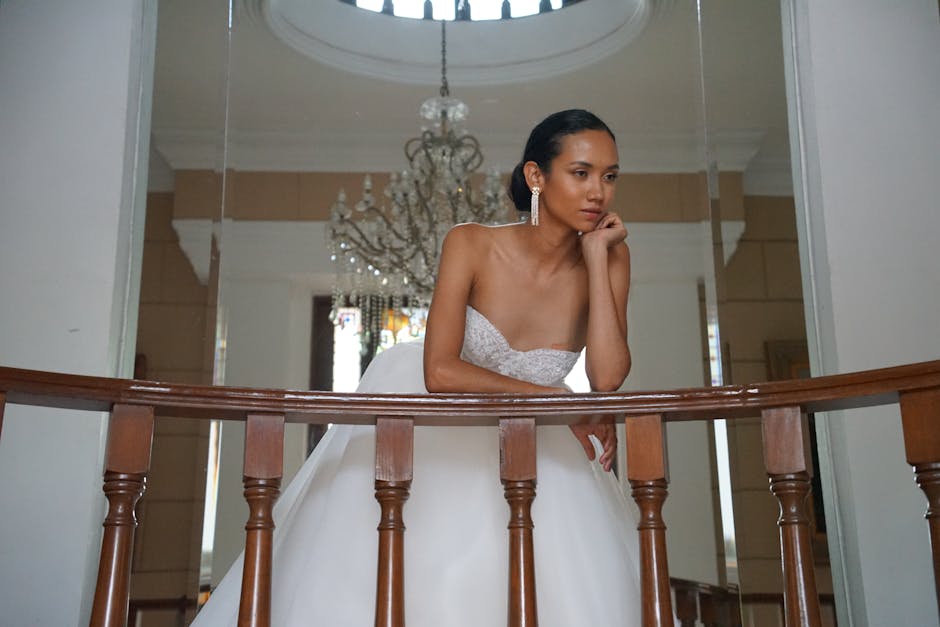 A bride poses gracefully indoors, showcasing elegance and sophistication in a white gown.